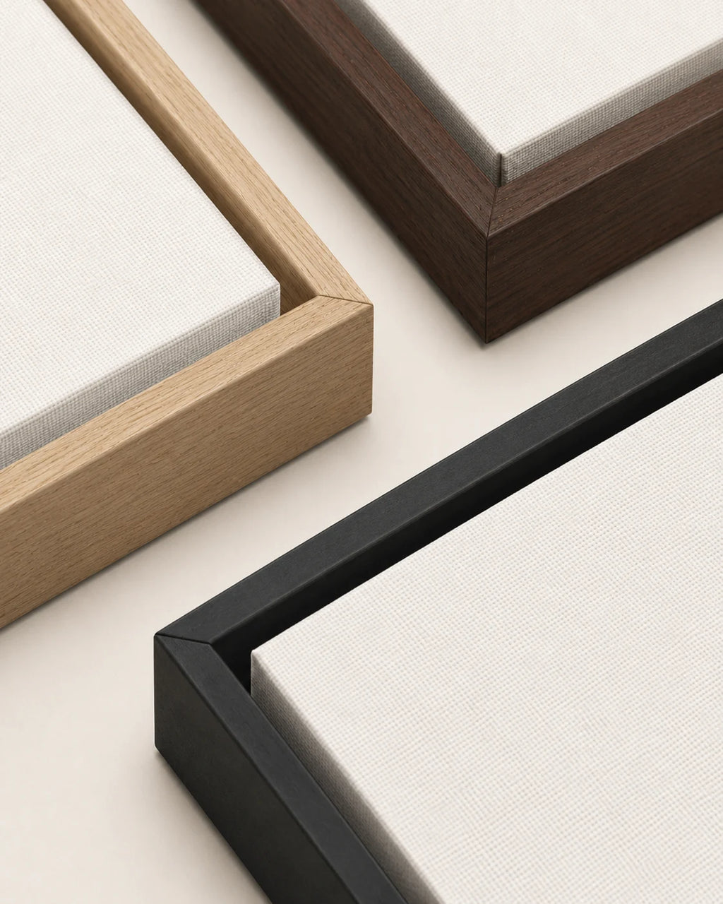 The three framed canvas mouldings side by side in natural wood, dark wood and black, each showing the floating gap and the woven canvas